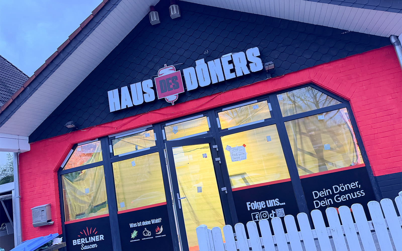 Außenansicht der fast fertigen "Haus des Döners"-Filiale in Hückelhoven mit markantem Logo und Werbeslogans auf den Fenstern, kurz vor der Eröffnung.